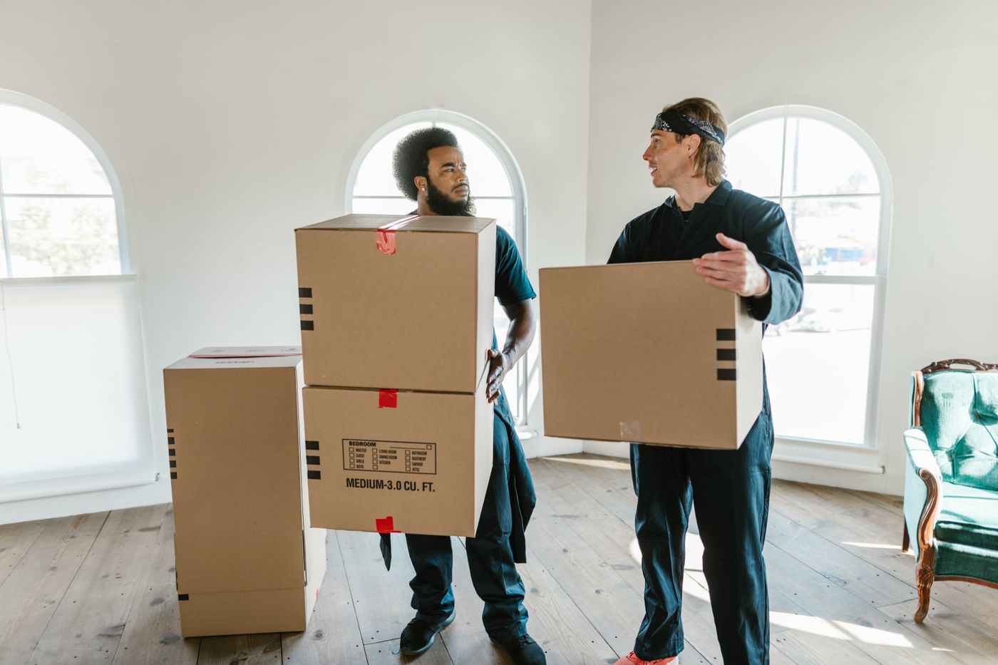 Two movers carrying cardboard boxes in a bright room